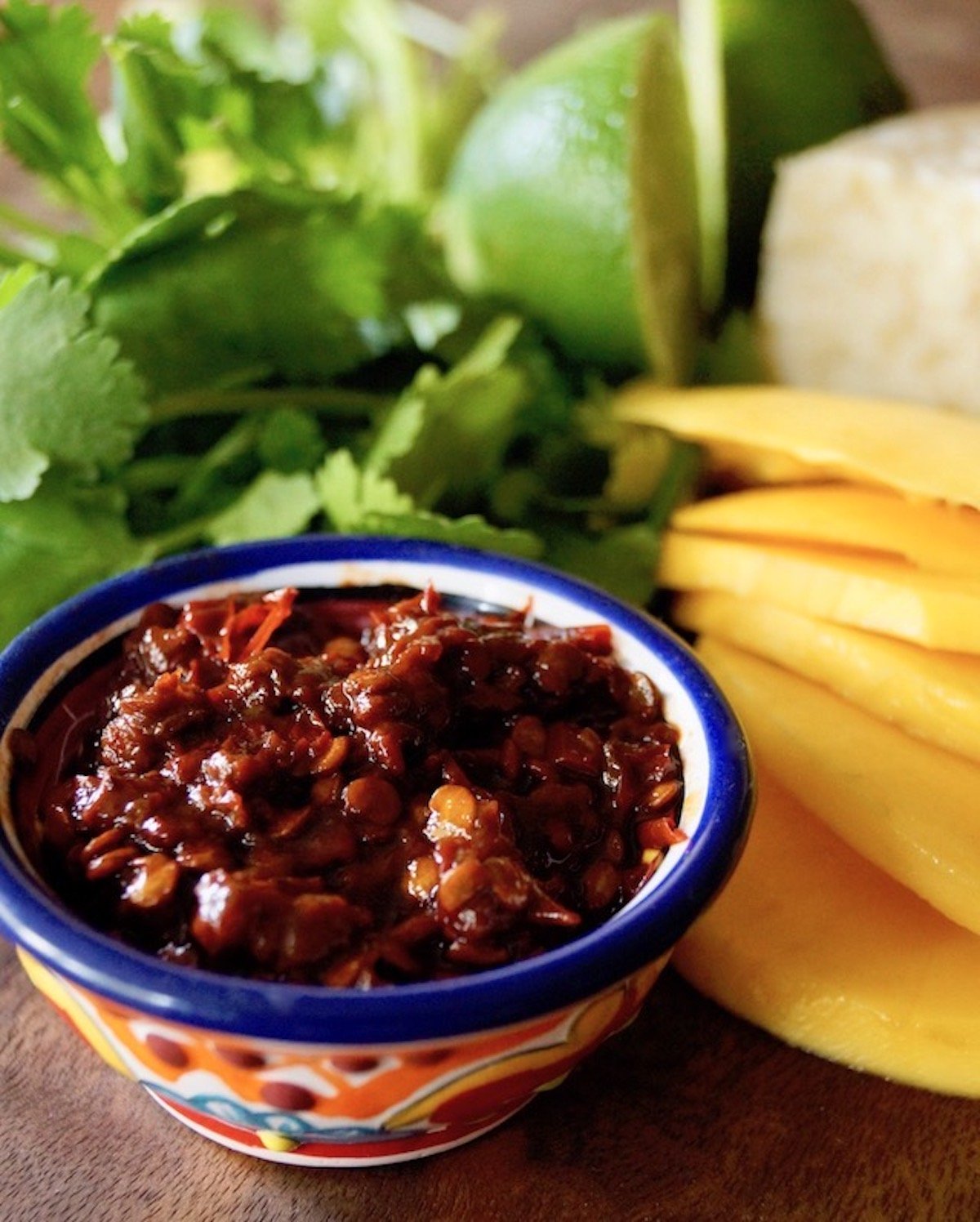 Mango slices, cilantro and a small bowl of chipotles peppers in adobo.