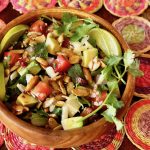 top view of a Mexican chopped salad in a wooden bowl, on a colorful placemat.