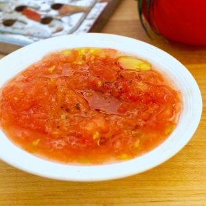 White bowl filled with grated tomatoes and olive oil.