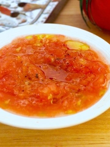 White bowl filled with grated tomatoes and olive oil.