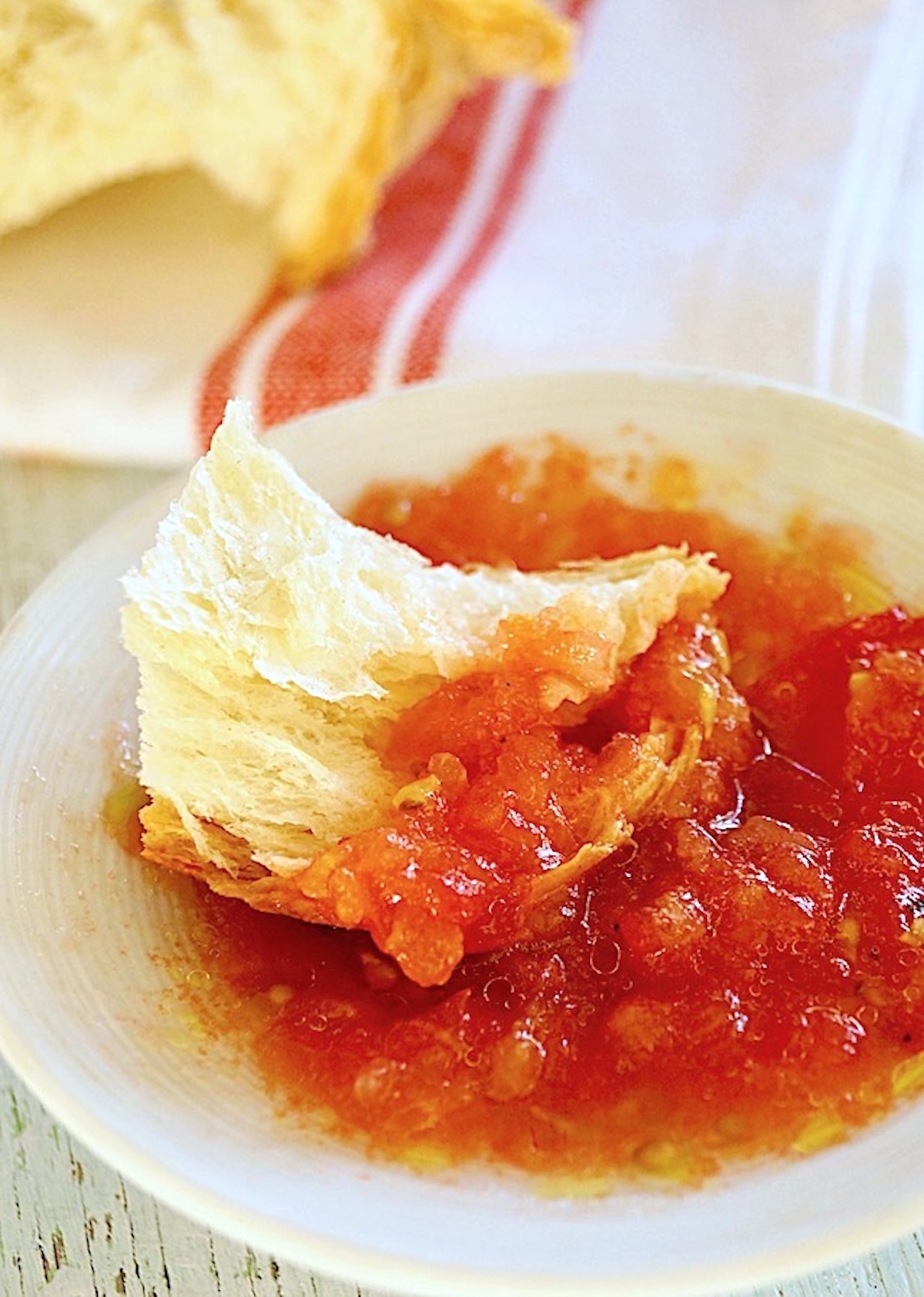 Sweet-Breakfast-Grated-Tomatoes-with-Olive-Oil Grated tomatoes in a small white bowl with a piece of rustic bread.