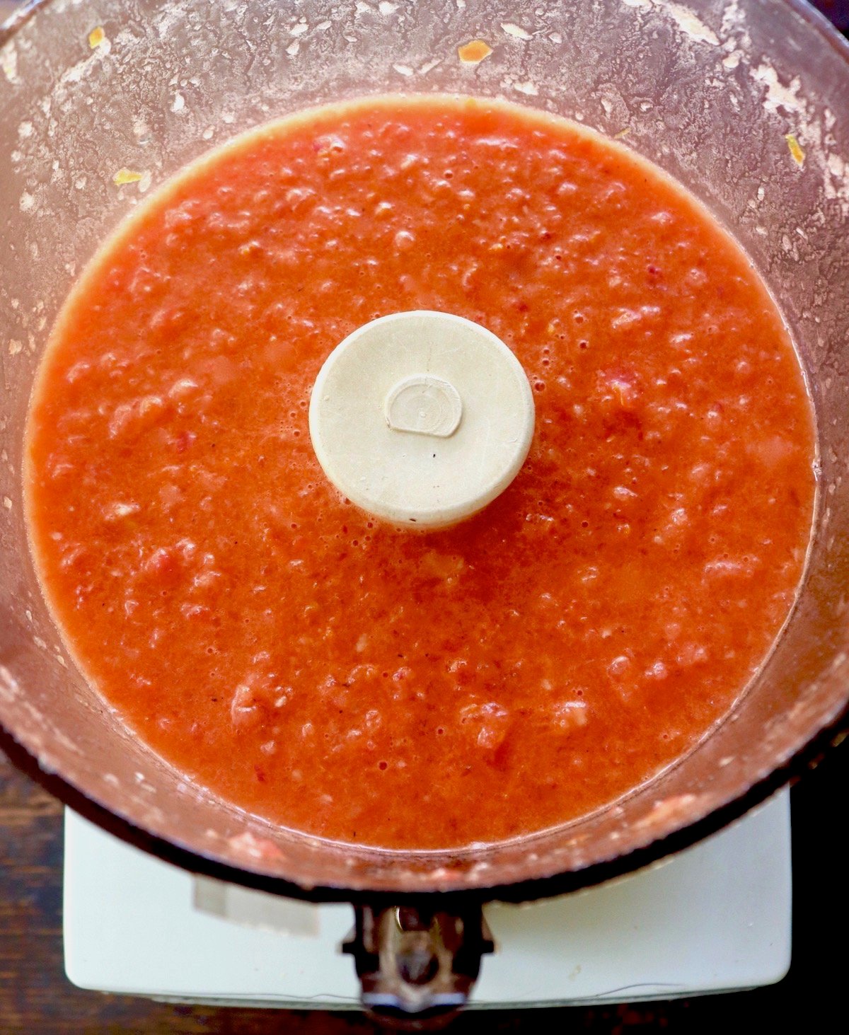 Food processor bowl filled with red tomato gazpacho.