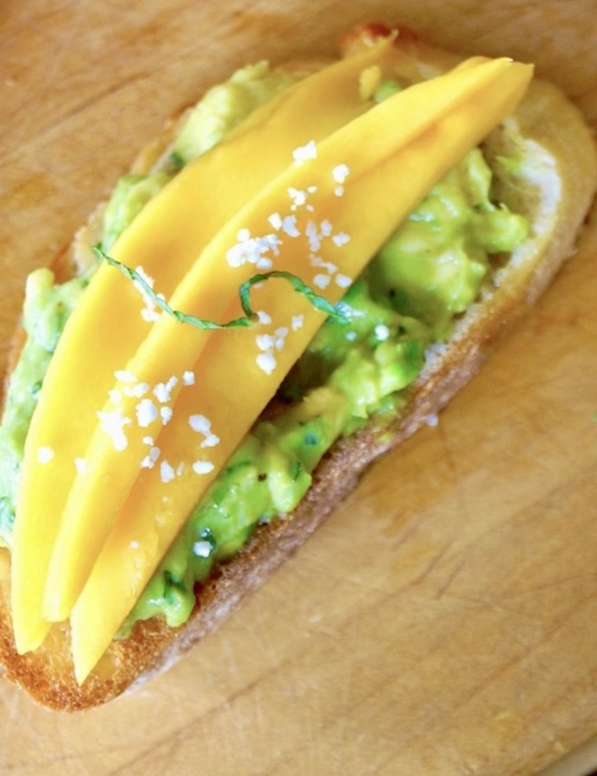 Avocado toast with a few mango slices on top, with a light Feta cheese sprinkling.