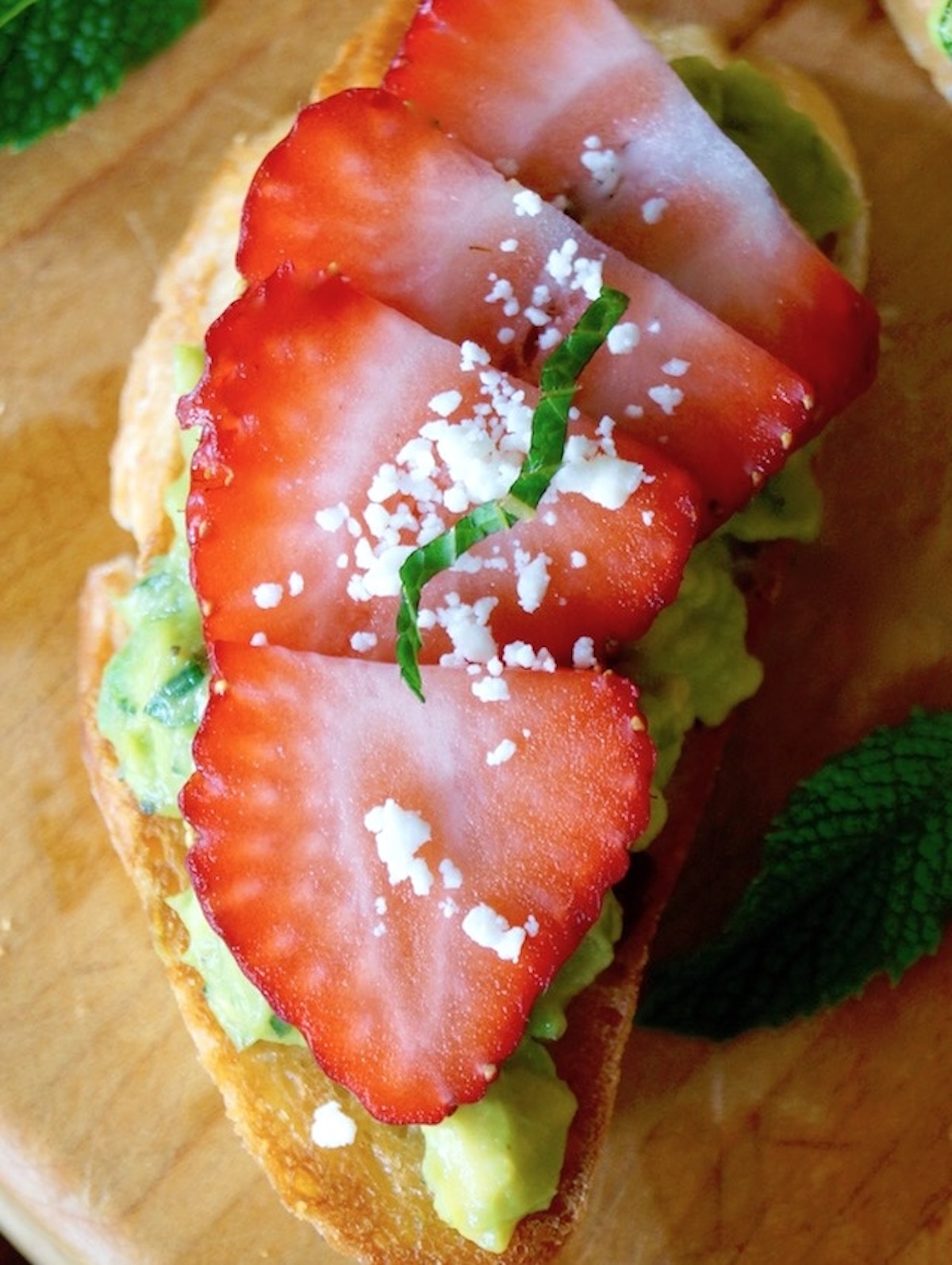 Avocado toast with a few strawberry slices on top, with a light Feta cheese sprinkling.