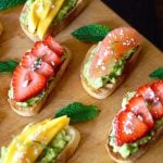 5 pieces of avocado toast with strawberries, grapefruit and mango.