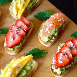 5 pieces of avocado toast with strawberries, grapefruit and mango.