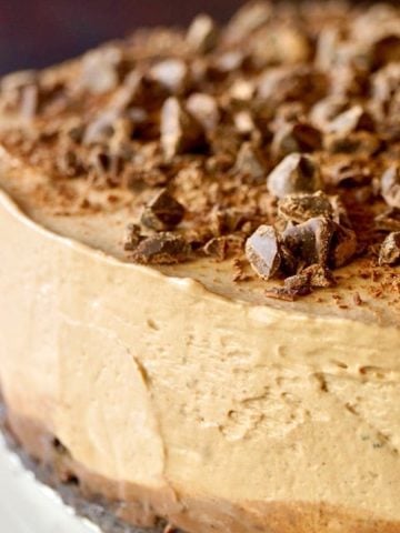 Close up of the edge of No-Bake Espresso Cheesecake with Ganache on white plate.