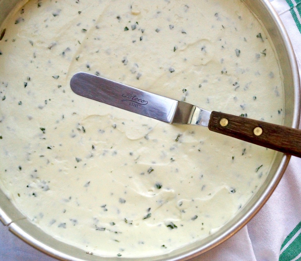 Basil cheesecake filling spread evenly on top of cookie crust in a springform pan.