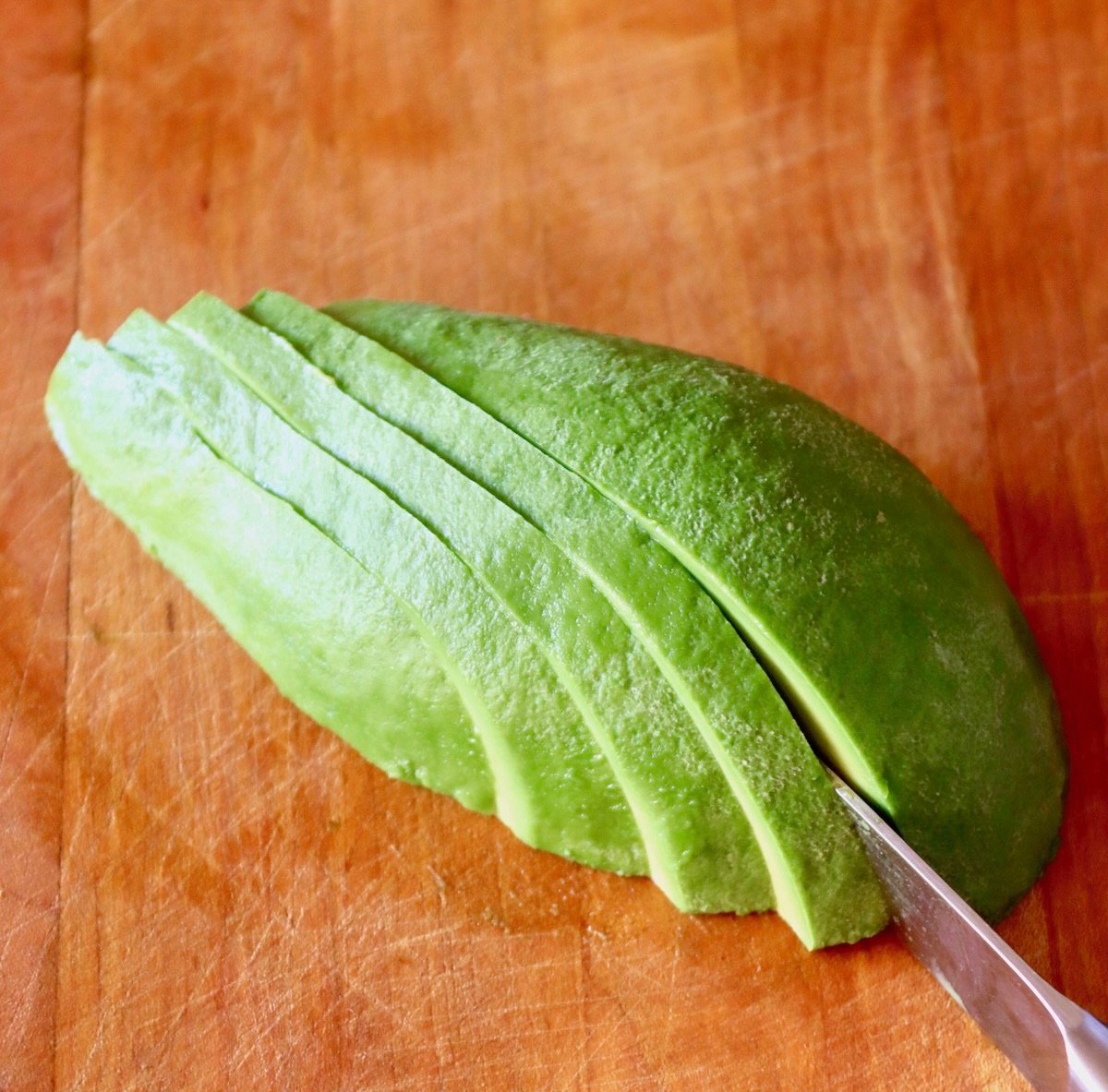 Avocado-Fries Half an avocado with skin removed, being sliced.