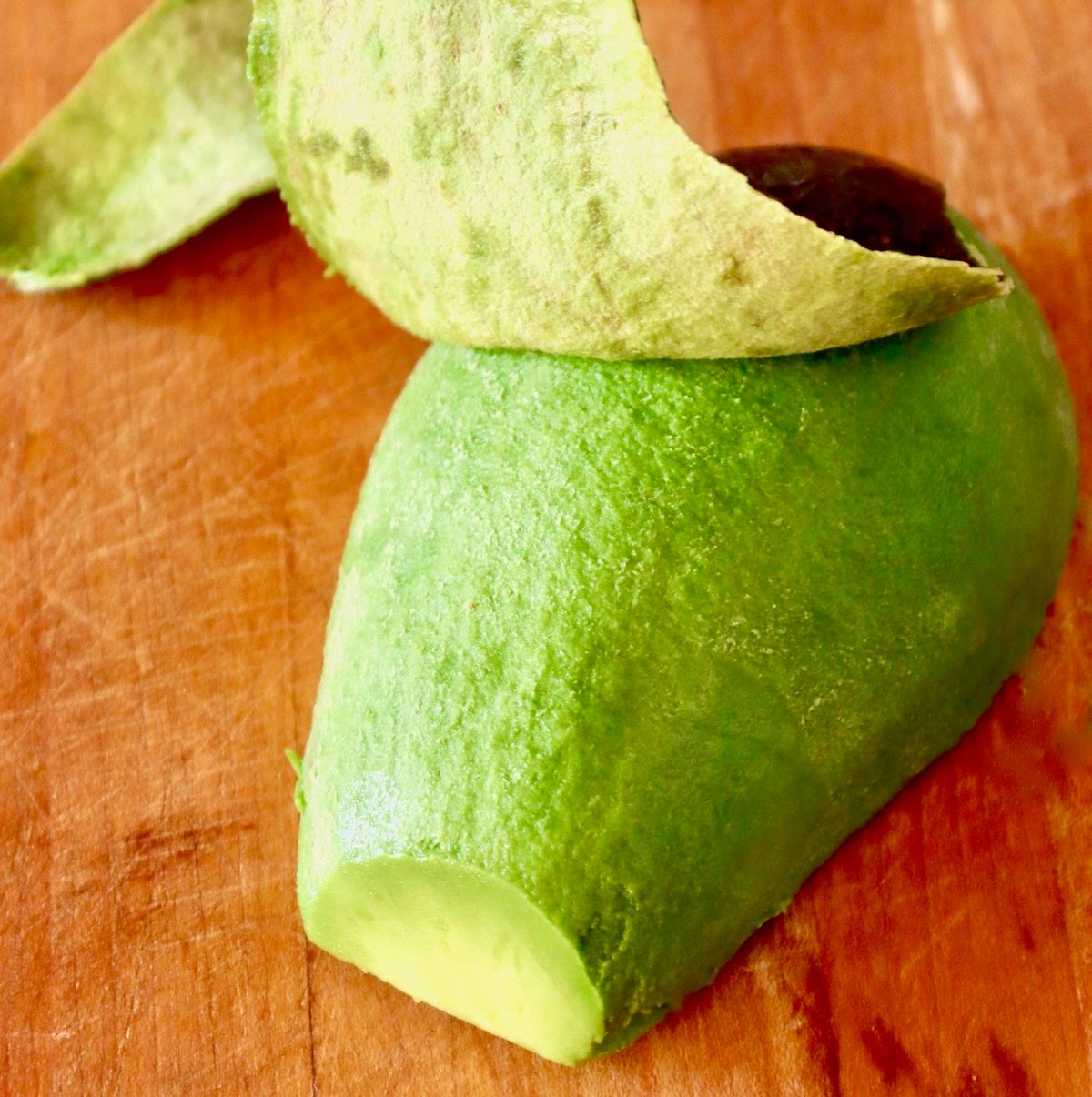 Avocado-Fries Half an avocado, round side up, with skin being peeled off.