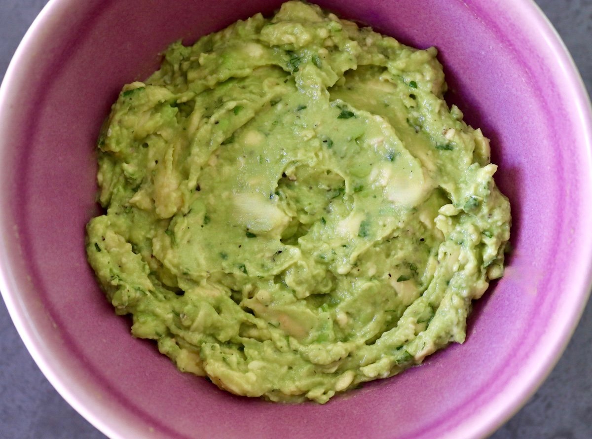 Avocado and mint mixture in a purple bowl -- it looks like guacamole.