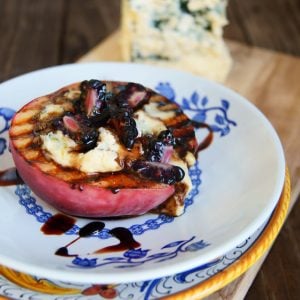 grilled peach with blue cheese and blackberries on white and blue plate