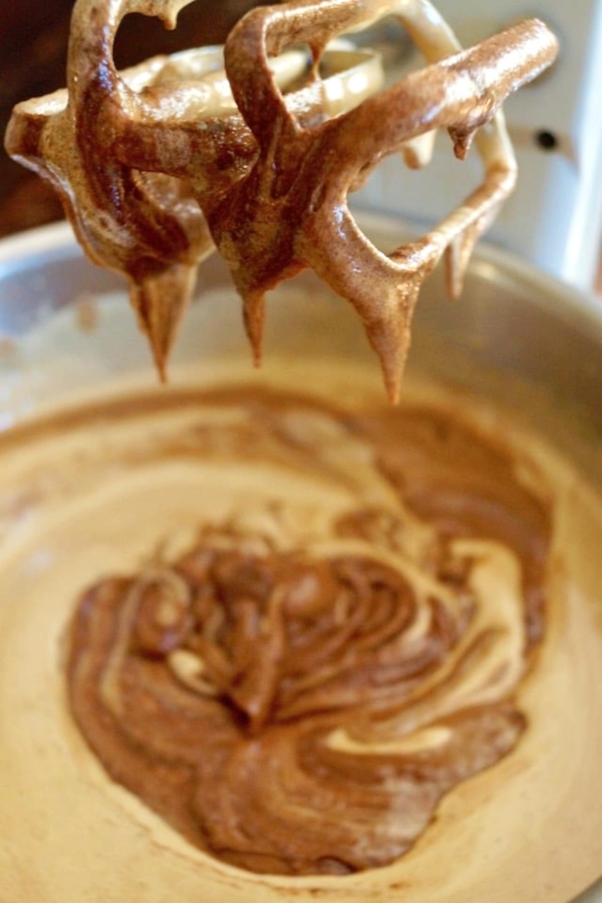 Brownie batter in a pan with baking beaters above it.