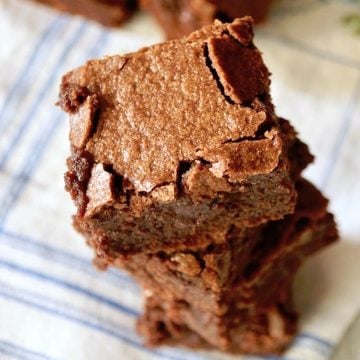 Short stack of square brownies on blue and white cloth napkin.