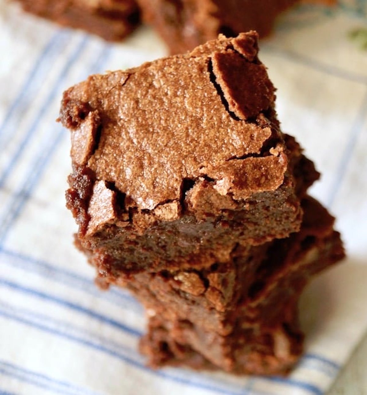 Short stack of square brownies on blue and white cloth napkin.