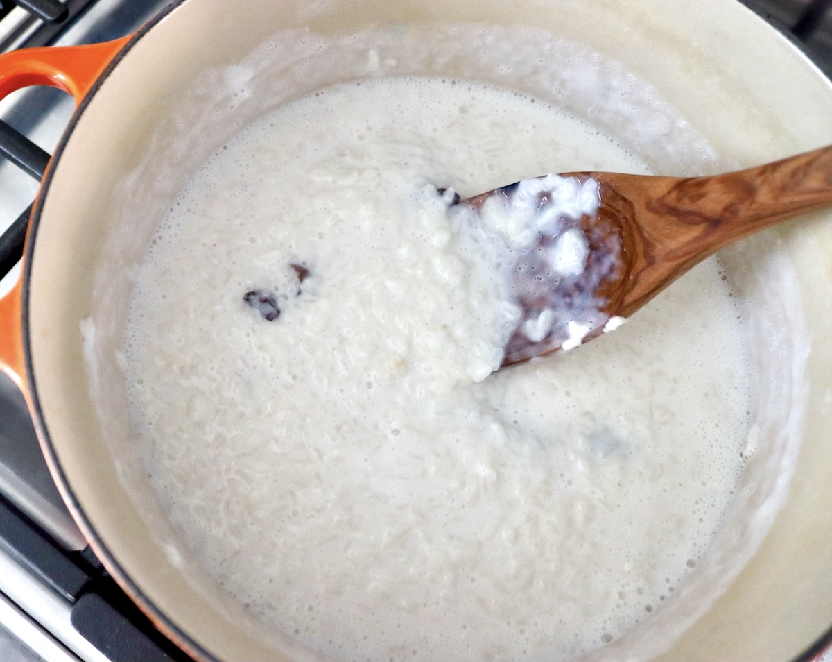 How-to-Make-Rice-Pudding Lots of milk with cooked rice and wooden spatula in a Dutch oven.