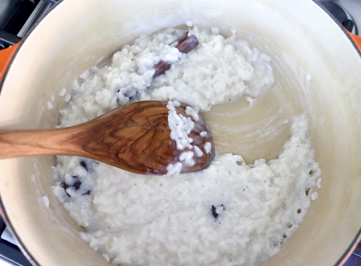 How-to-Make-Rice-Pudding Cooked rice with star anise and a wooden spatula that's making a path in the rice.