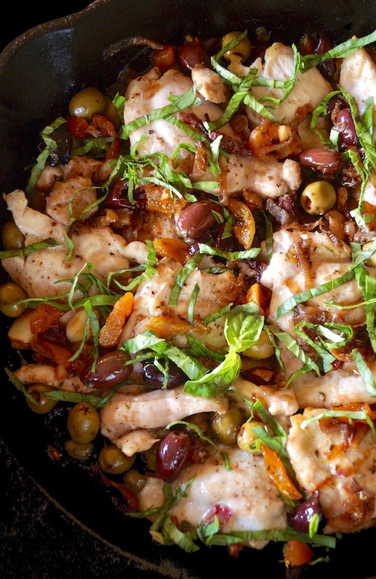 Cast iron skillet with apricot and olive chicken thighs.