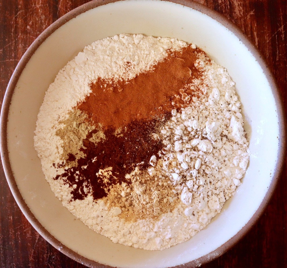 Spices and flour in a cream-colored ceramic mixing bowl.