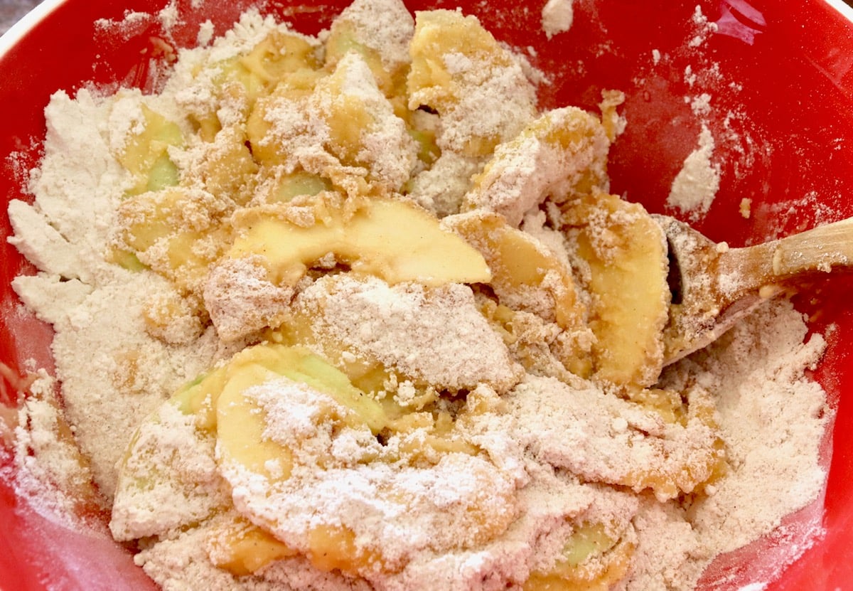 Chai cake flour and spic mix with apple slices in a red bowl.