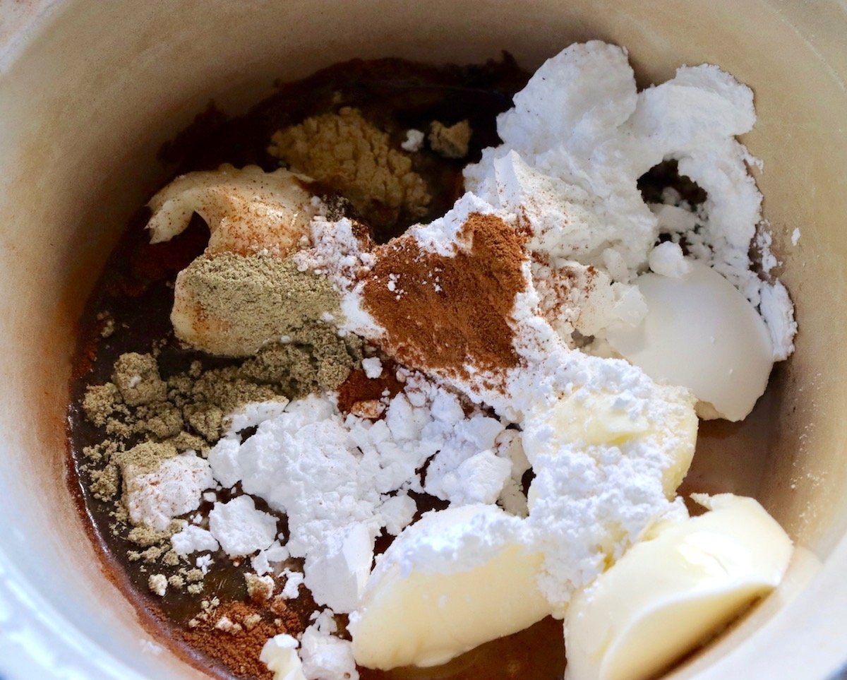 Chai spice glaze ingredients in a sauce pan including powdered sugar, chai spices, butter and water.