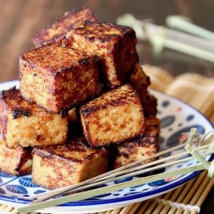 stacked cubes of tofu with miso marinade on white and blue plate on sushi mat