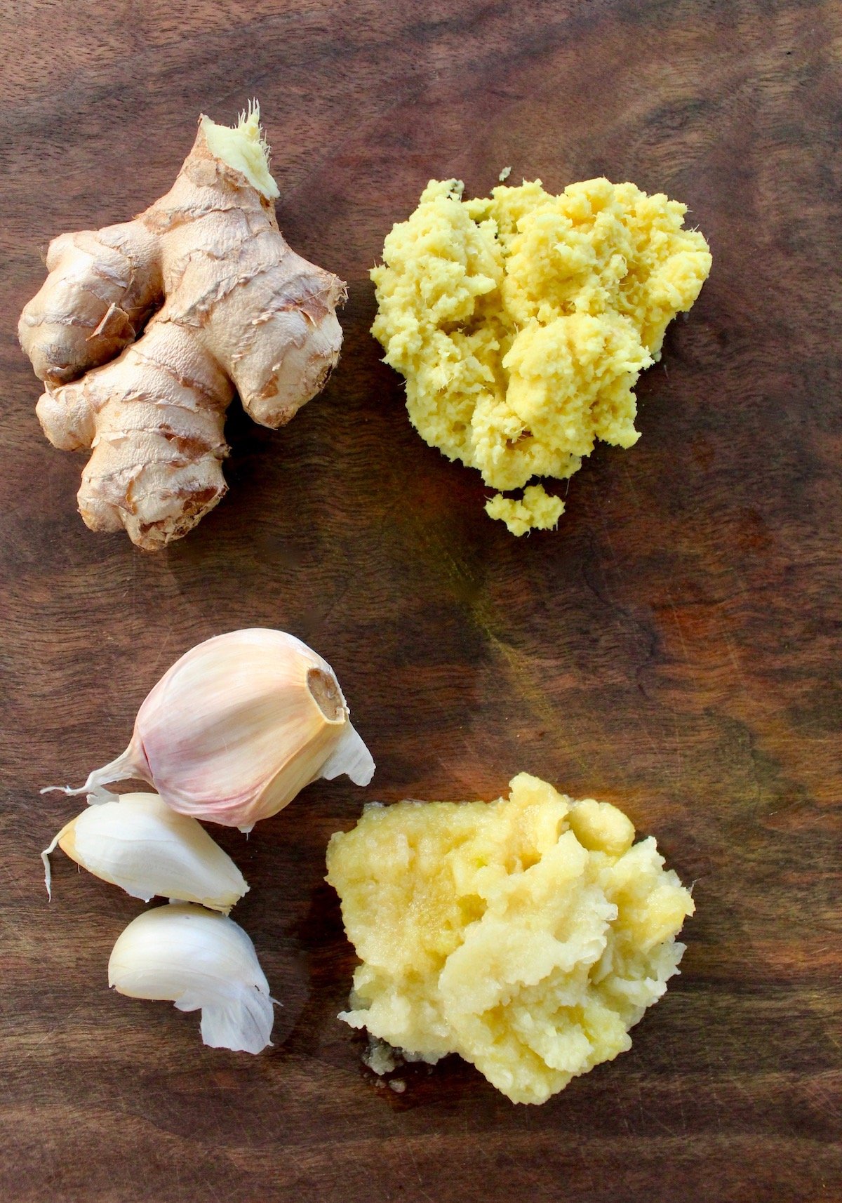 ginger and garlic pulp on cutting board with garlic cloves and ginger finger