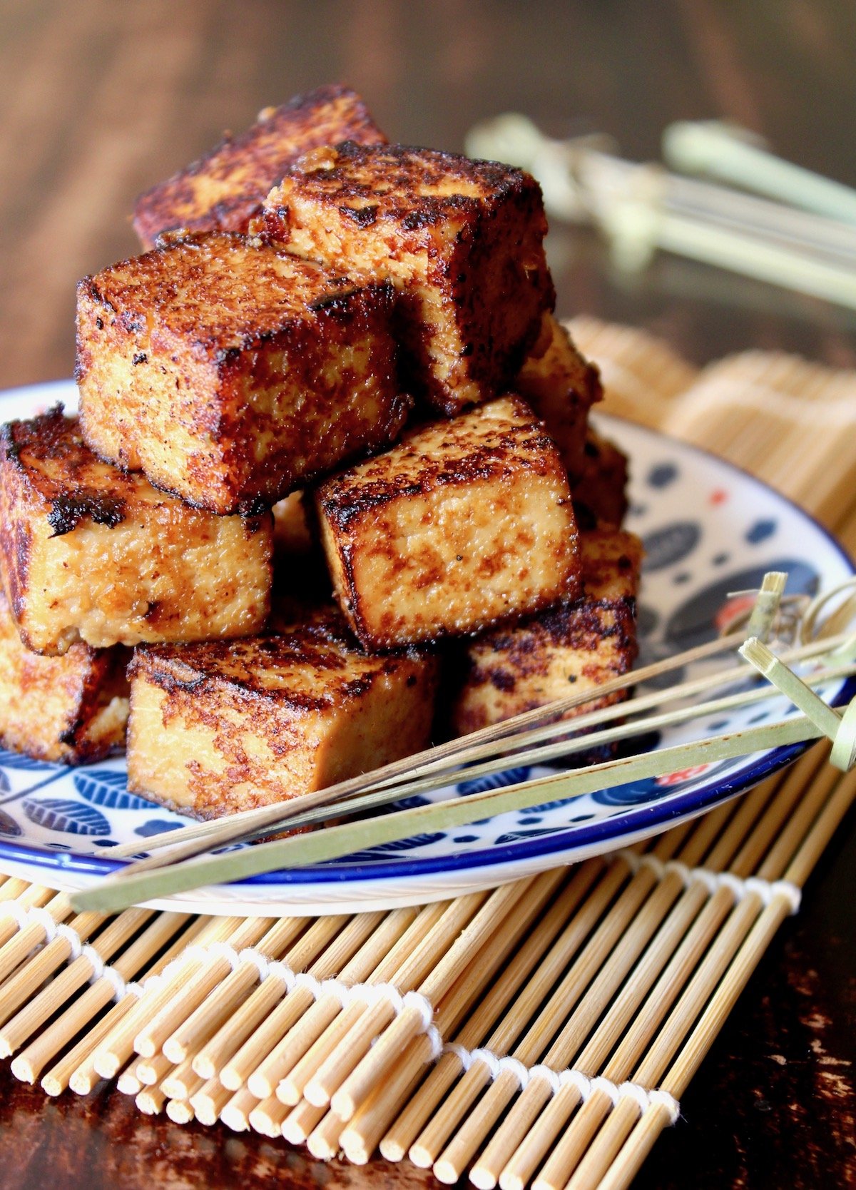 stacked cubes of tofu with miso marinade on white and blue plate on sushi mat