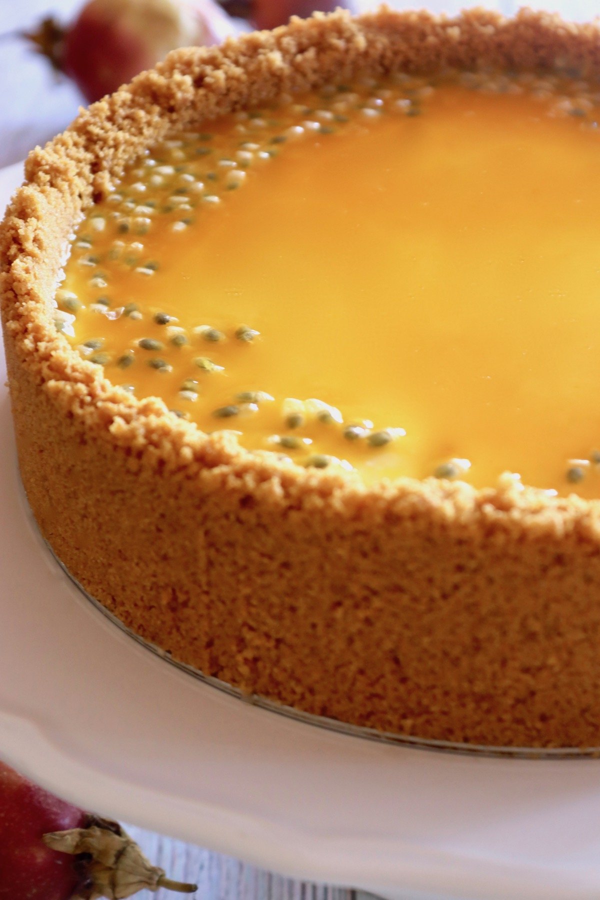 Whole Passion Fruit Cheesecake with cookie crust on a white platter.