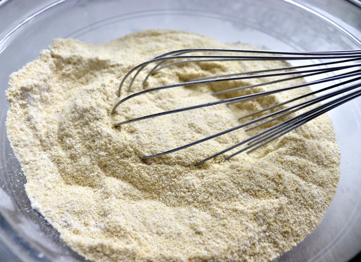 Bowl with a whisk and mixed cornmeal, flour, sugar, cumin and salt.