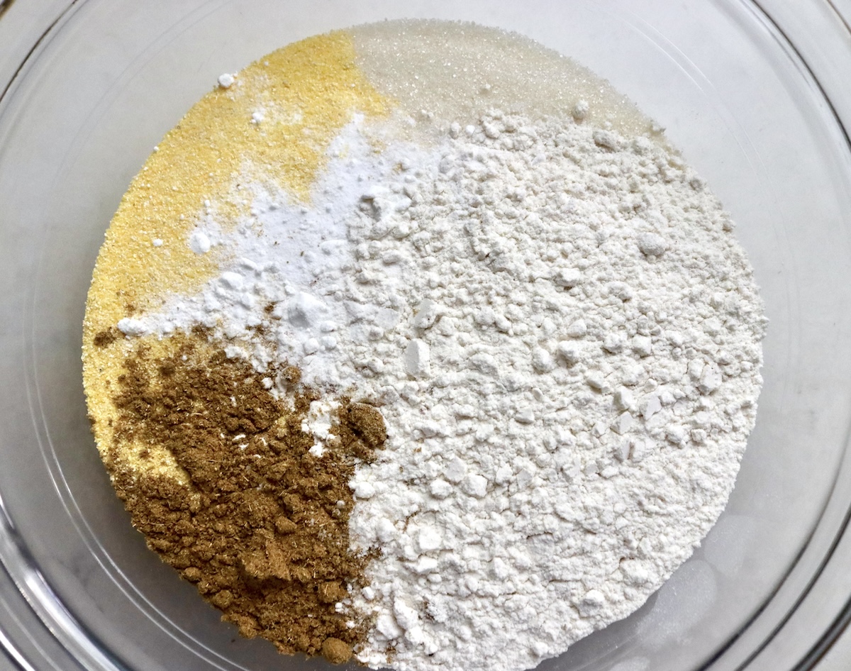 Glass bowl wtih gluten-free flour, baking soda, cornmeal, cumin, salt, and sugar.