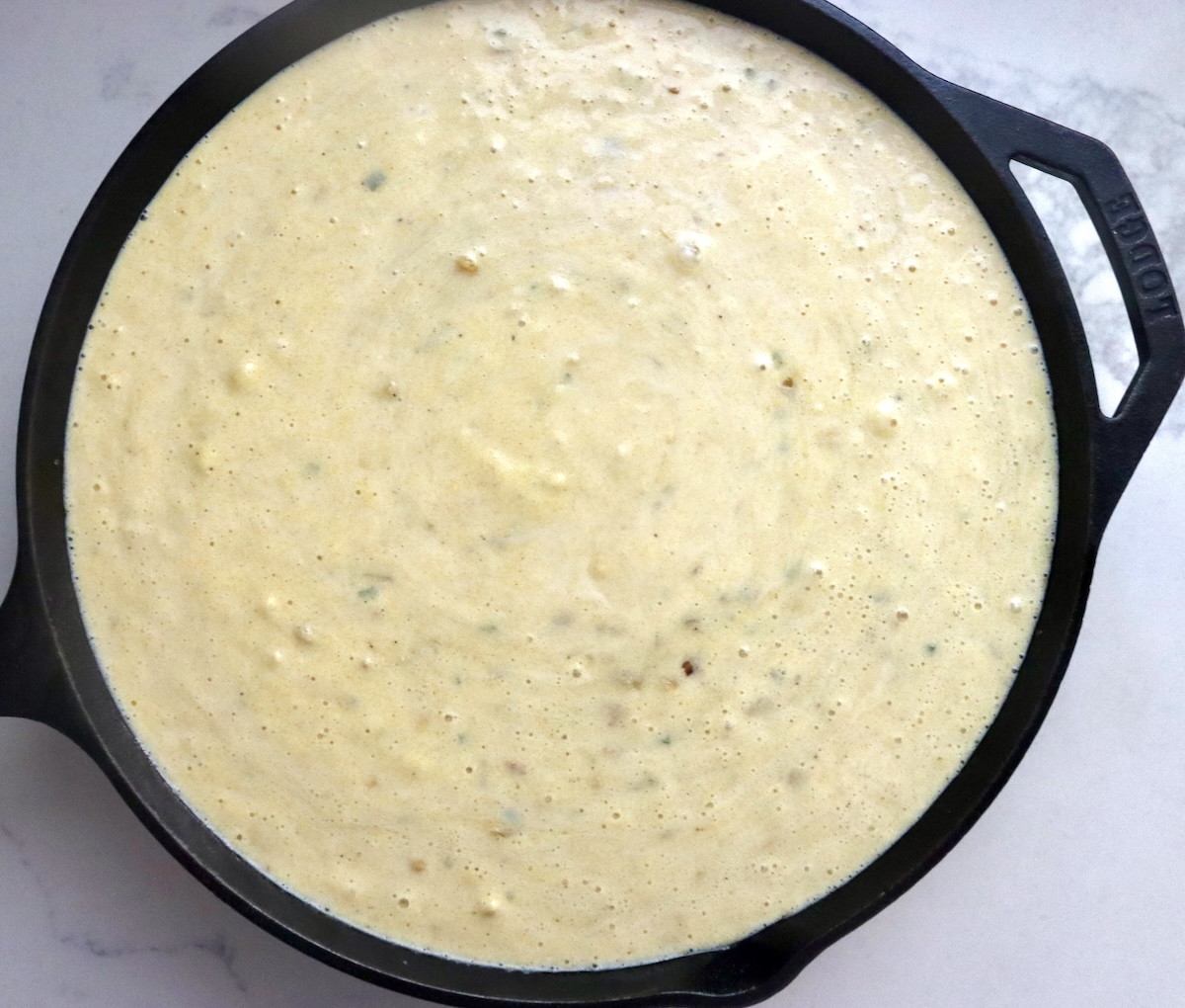 Cast iron skillet filled with bacon jalapeno cornbread batter.