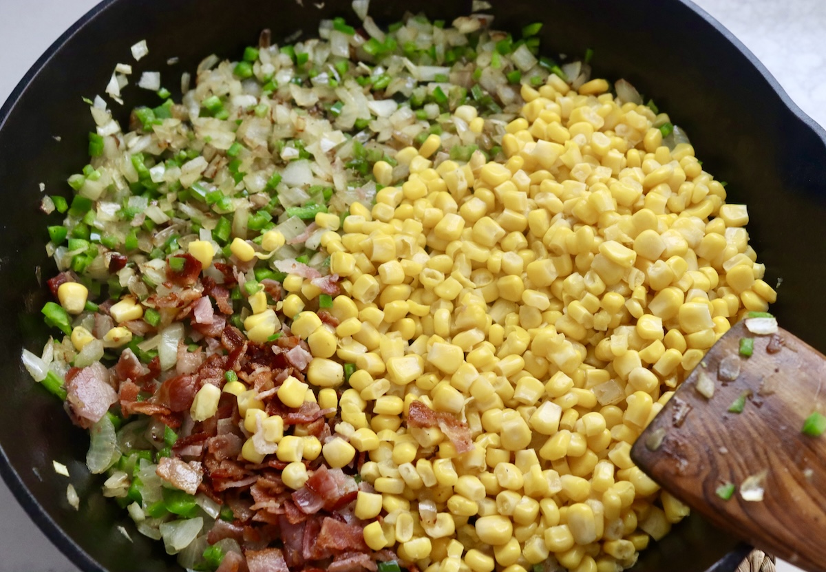 Diced onion, jalapeno, corn kernels and crumbled bacon in a cast iron skillet - not mixed.