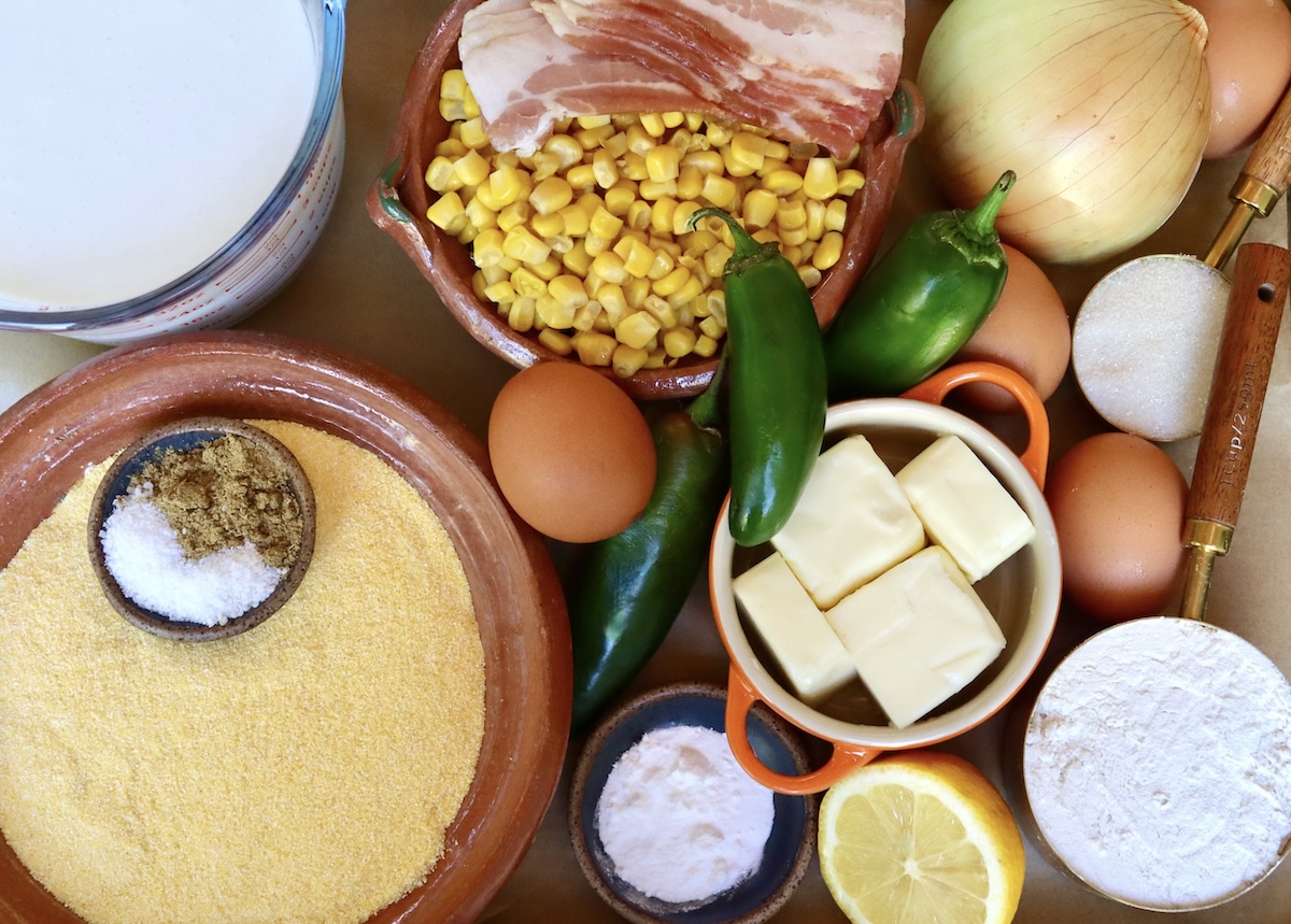 Ingredients for bacon jalapeno cornbread including: raw bacon, corn kernels, jalapeno peppers, butter, eggs, flour, corn meal, cumin, salt and sugar.