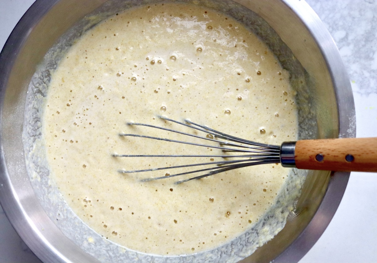 Cornbread batter in a mixing bowl with a whisk.