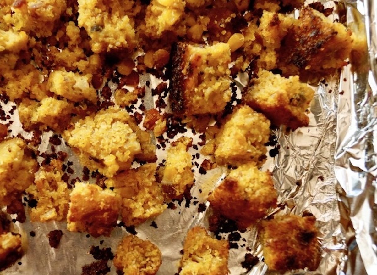 Cornbread croutons on a foil-lined sheet pan.