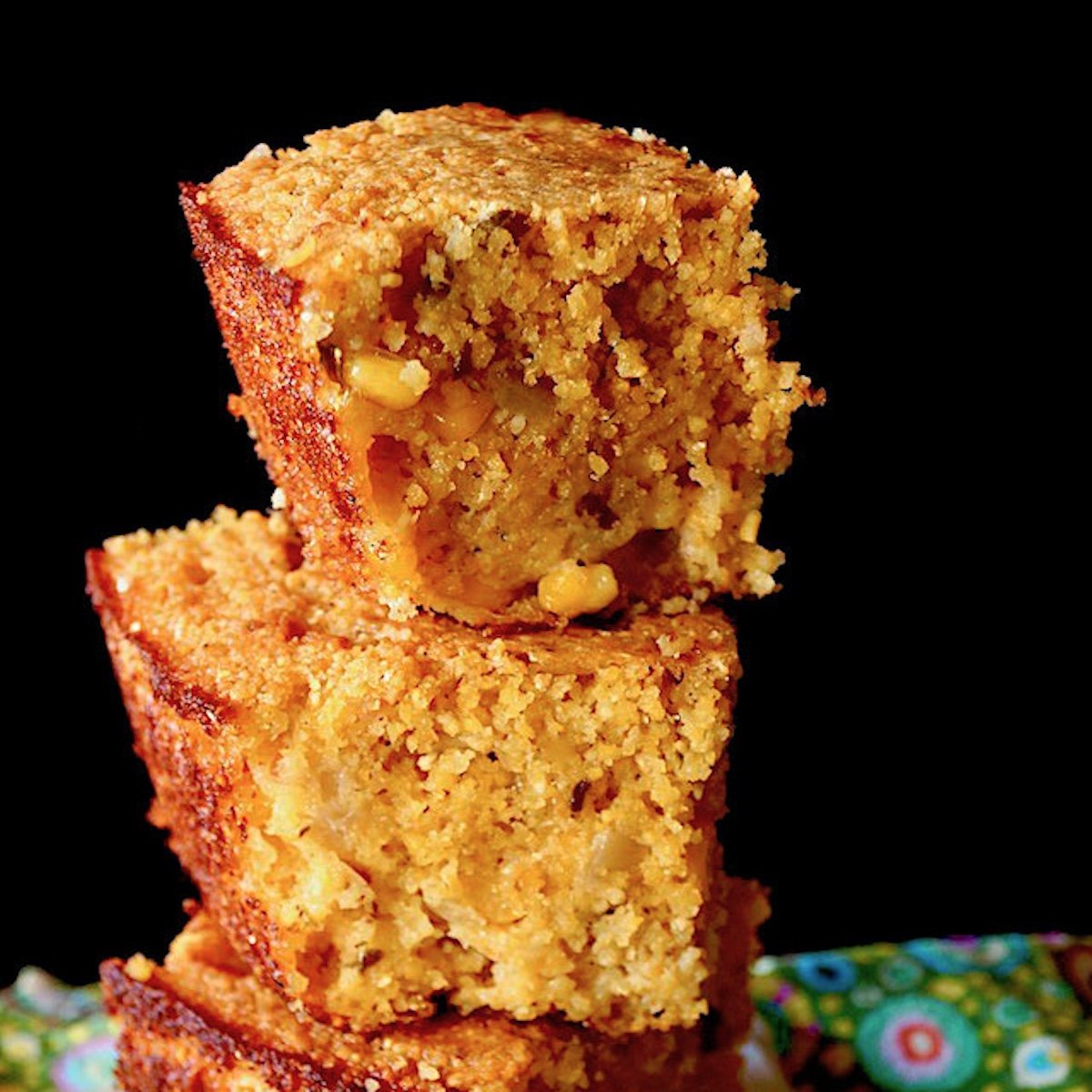 Stack of three square pieces of cornbread with black background.