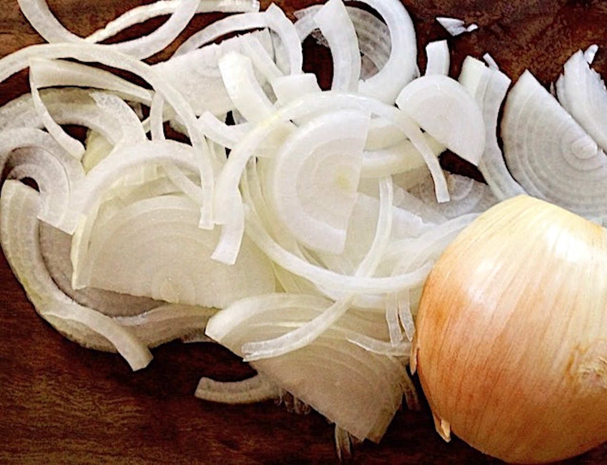 pile of white onion slices and half onion.