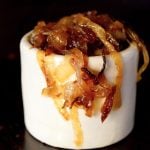 Small cream-colored dish filled with soft, deep golden caramelized onions.