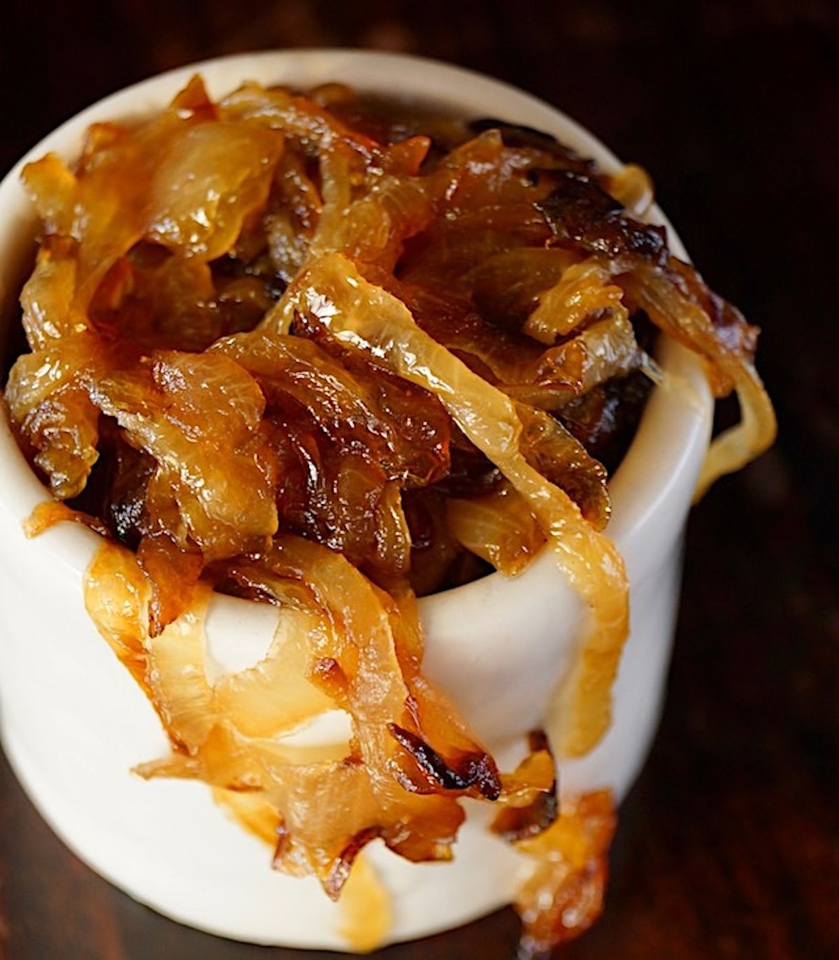 Small cream-colored dish filled with soft, deep golden caramelized onions.