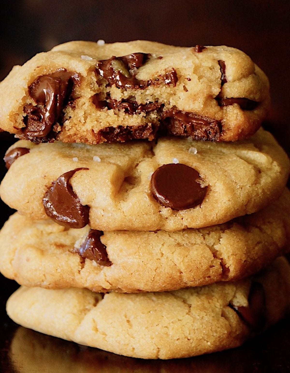 small stack of chocolate chip cookies with the top one broken in half.