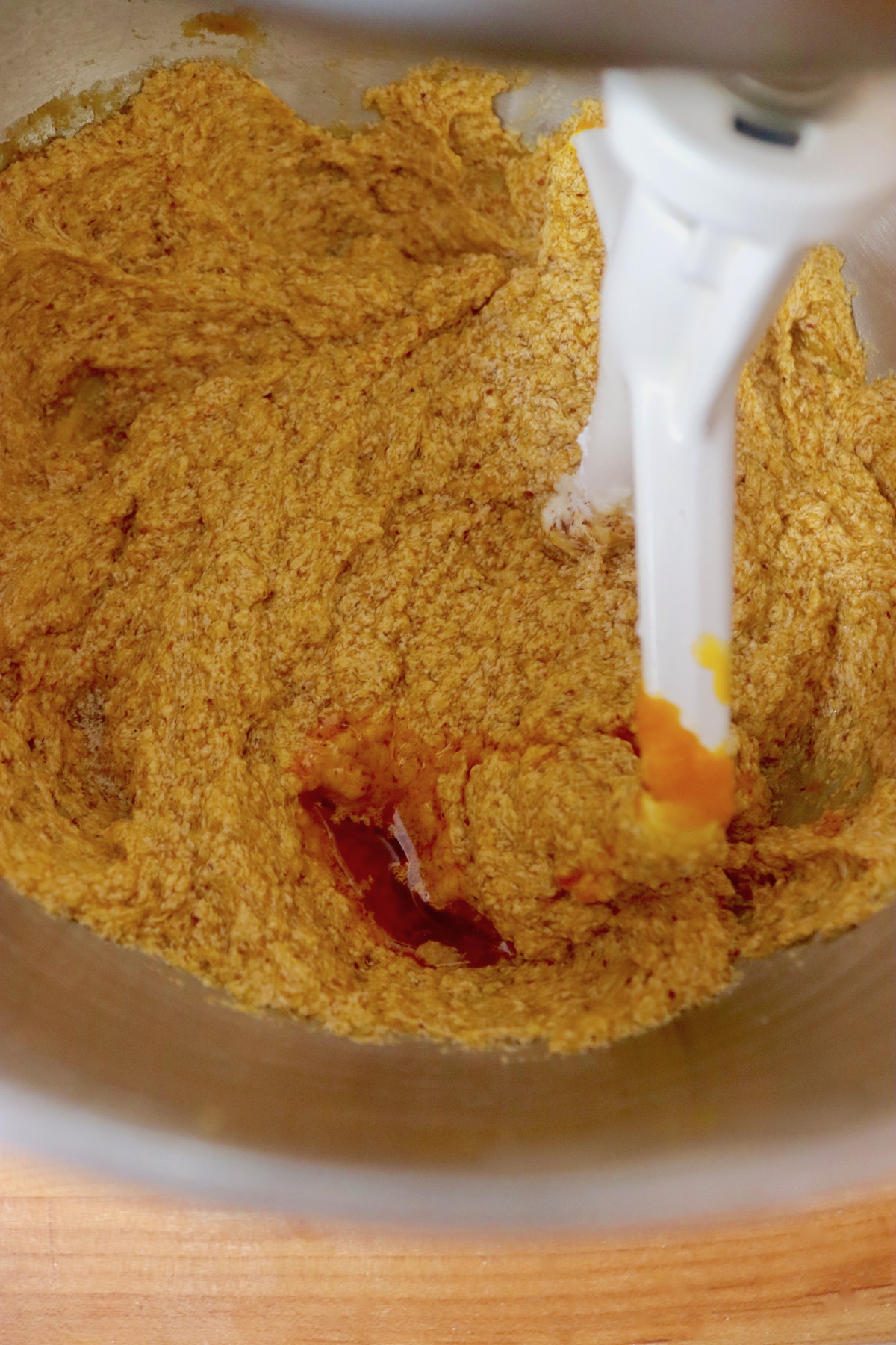Pumpkin cookie dough in mixer bowl with a drop of dark orange coloring.