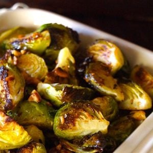 Super browned quartered brusssels sprouts in a red baking dish.