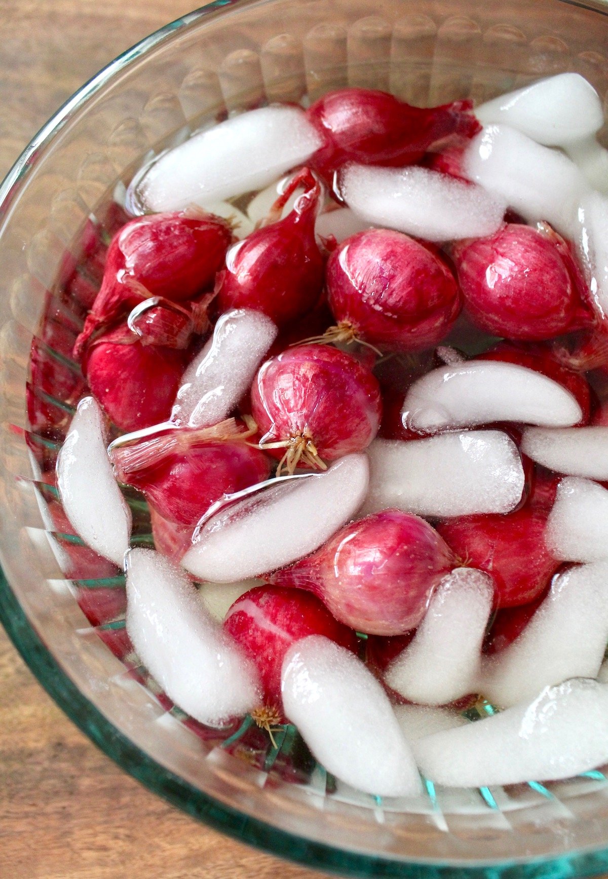 red pearl onions in bowl of ice water