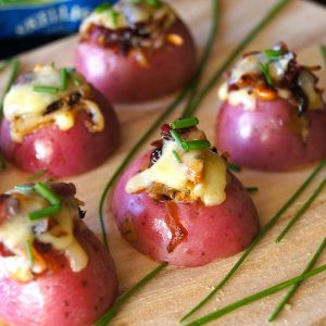 A few Mini Red Potato Appetizer with Cranberries on a wood cutting board with fresh chives.