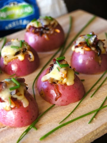 A few Mini Red Potato Appetizer with Cranberries on a wood cutting board with fresh chives.