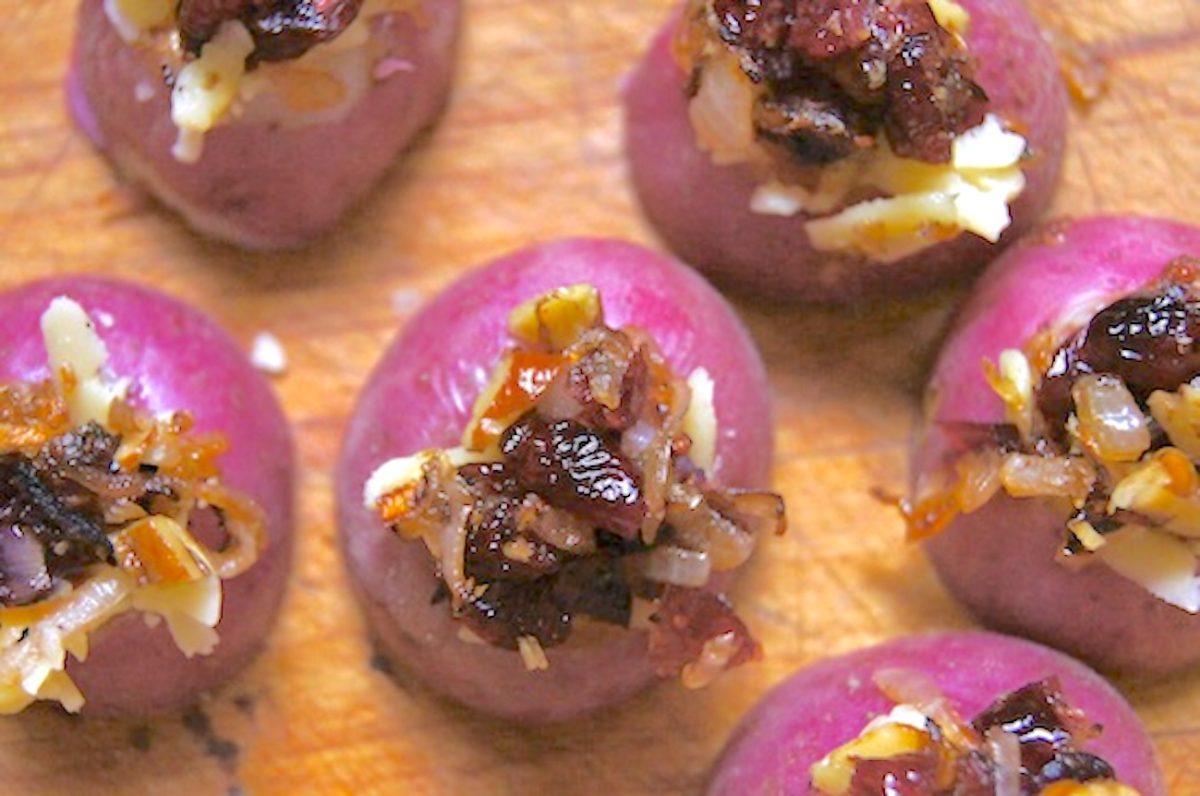 Mini-Red-Potato-Appetizer-with-Cranberries Several small red potatoes, halved, with a tiny hole taken out of the tops that's filled with cranberry and onion.