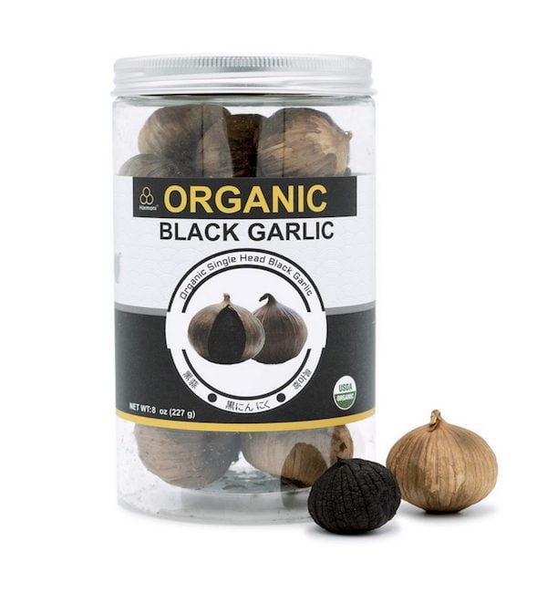 Jar filled with organic black garlic with black and yellow label.
