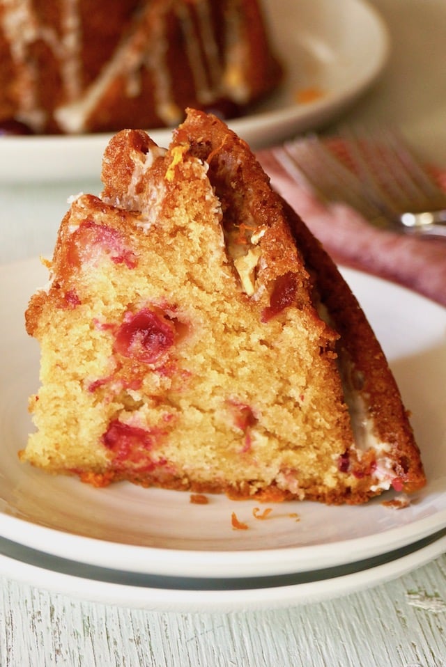 big slice of cranberry orange cake with amaretto glaze on white plate