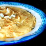 Bright blue-rimmed bowl with creamy polenta with gorgonzola sprinkled on top.